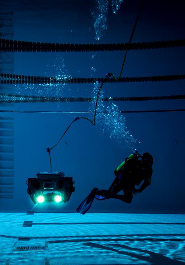 Student swimming with robot underwater in swimming pool